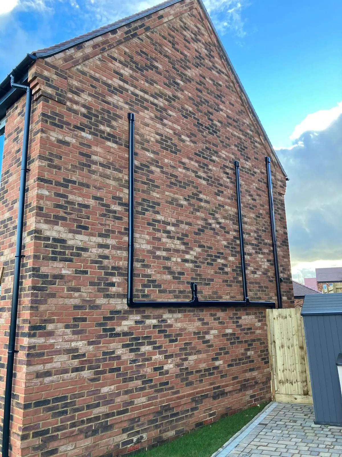 External pipework running up brick gable wall