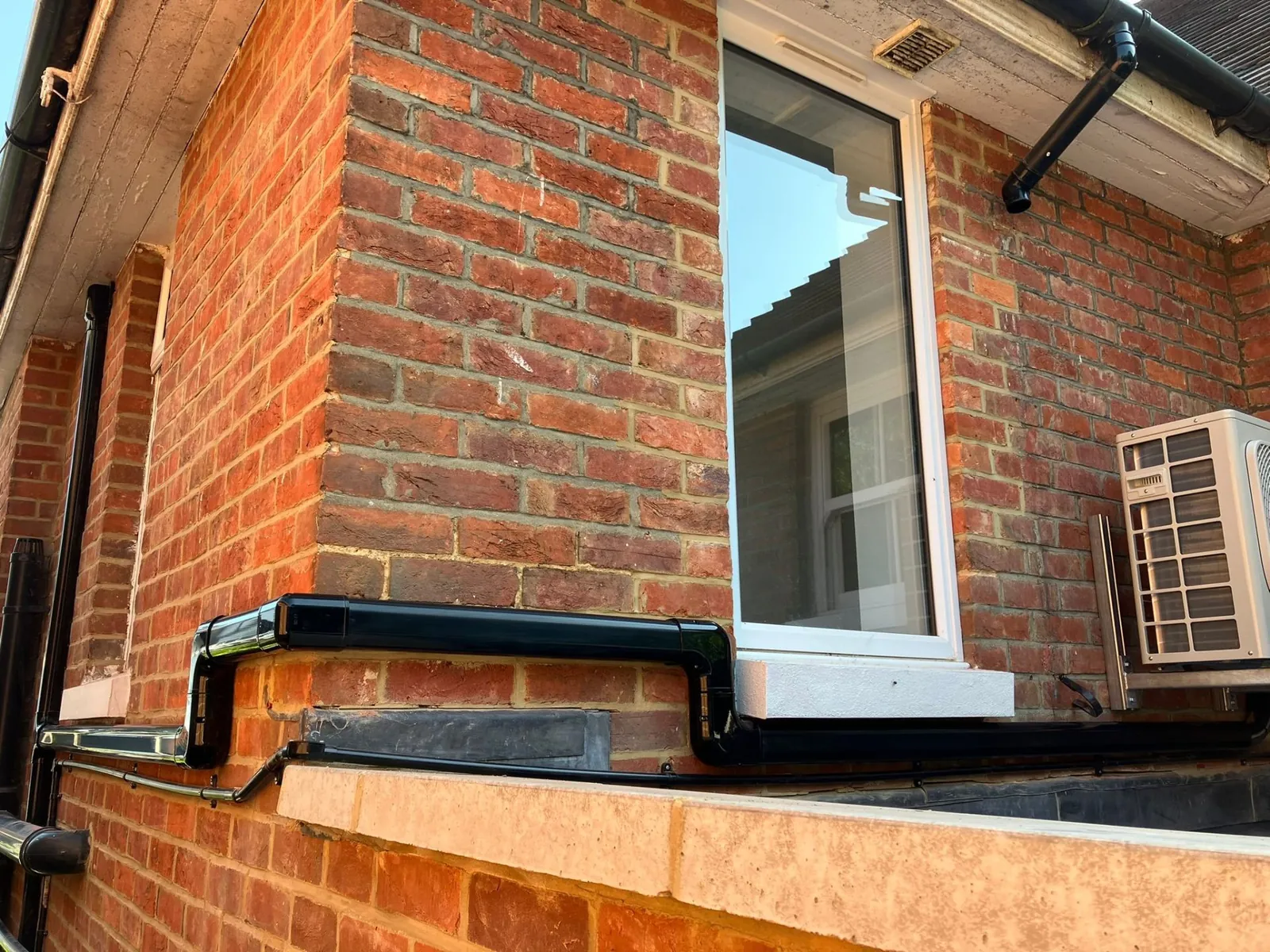External AC pipework and condenser on brick wall