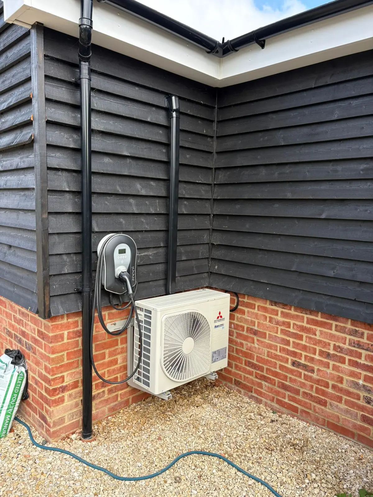 Mitsubishi outdoor unit alongside EV charger on barn conversion